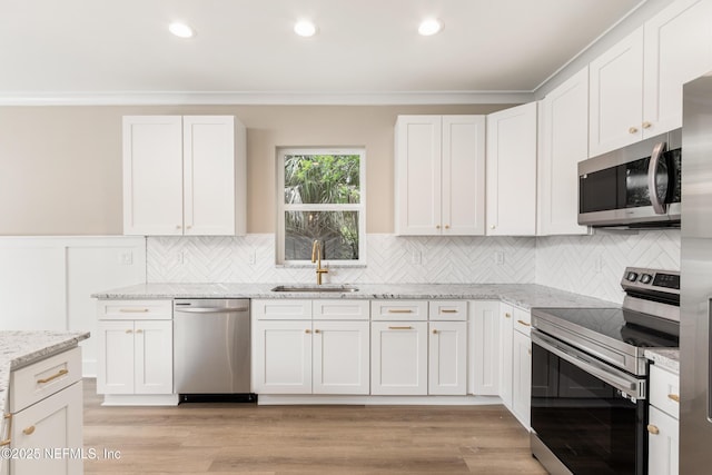 6334 Salado Rd, Saint Augustine, FL 32080 - kitchen featuring stainless steel appliances, light stone countertops, white cabinets, recessed lighting, and wainscoting