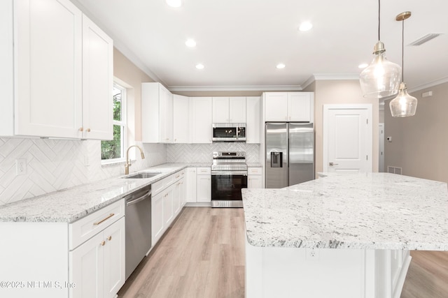 6334 Salado Rd, Saint Augustine, FL 32080 - kitchen featuring appliances with stainless steel finishes, ornamental molding, light wood-style flooring, light stone counters, and a kitchen island