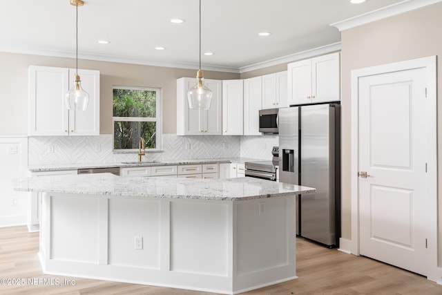 6334 Salado Rd, Saint Augustine, FL 32080 - kitchen featuring appliances with stainless steel finishes, ornamental molding, decorative backsplash, white cabinetry, and a kitchen island