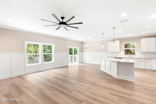 6334 Salado Rd, Saint Augustine, FL 32080 - kitchen featuring a chandelier, white cabinets, a decorative wall, ceiling fan, and light stone countertops