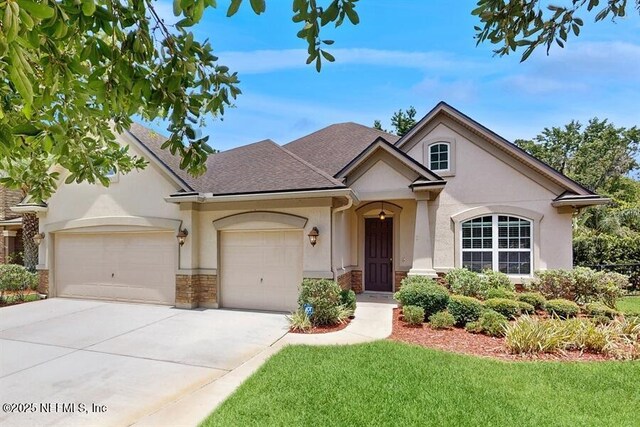 1911 Salt Creek Dr, Fleming Island, FL 32003 - view of front of property featuring stucco siding, an attached garage, driveway, a front lawn, and a shingled roof