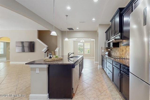 1911 Salt Creek Dr, Fleming Island, FL 32003 - kitchen featuring appliances with stainless steel finishes, light tile patterned floors, under cabinet range hood, backsplash, and a kitchen island with sink