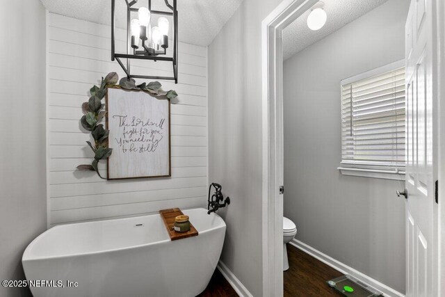 2346 Fairfield Ct, Fleming Island, FL 32003 - bathroom featuring a soaking tub, a textured ceiling, wood finished floors, and a chandelier