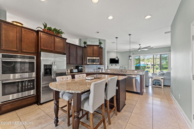 33114 Prairie Parke Pl, Fernandina Beach, FL 32034 - kitchen featuring appliances with stainless steel finishes, a peninsula, open floor plan, a kitchen island, and tasteful backsplash