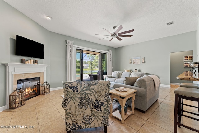 33114 Prairie Parke Pl, Fernandina Beach, FL 32034 - living room featuring ceiling fan, a textured ceiling, light tile patterned floors, and a fireplace
