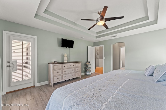 33114 Prairie Parke Pl, Fernandina Beach, FL 32034 - bedroom with a tray ceiling, arched walkways, wood finished floors, and ceiling fan