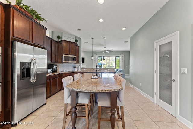 33114 Prairie Parke Pl, Fernandina Beach, FL 32034 - kitchen with stainless steel appliances, a breakfast bar area, light stone counters, recessed lighting, and light tile patterned floors