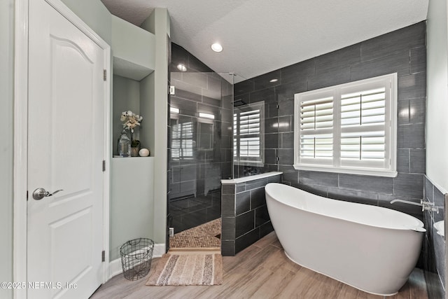 33114 Prairie Parke Pl, Fernandina Beach, FL 32034 - full bathroom featuring tile walls, a soaking tub, walk in shower, wood finished floors, and a textured ceiling
