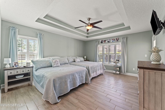 33114 Prairie Parke Pl, Fernandina Beach, FL 32034 - bedroom with multiple windows, a textured ceiling, a raised ceiling, and light wood finished floors