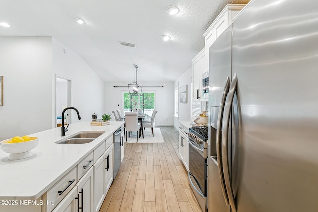 141 Balmoral Castle Dr, Saint Johns, FL 32259 - kitchen featuring appliances with stainless steel finishes, light wood-style floors, white cabinetry, lofted ceiling, and decorative light fixtures