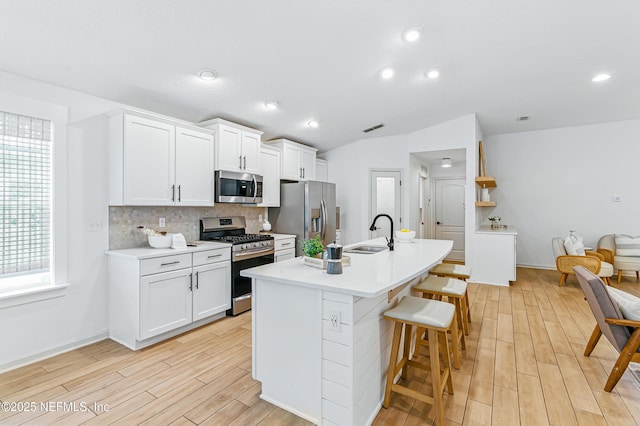 141 Balmoral Castle Dr, Saint Johns, FL 32259 - kitchen with stainless steel appliances, light wood finished floors, a breakfast bar, decorative backsplash, and an island with sink