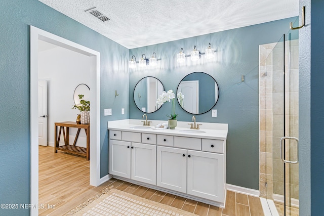 141 Balmoral Castle Dr, Saint Johns, FL 32259 - full bathroom with wood finish floors, a textured ceiling, double vanity, a shower stall, and a textured wall