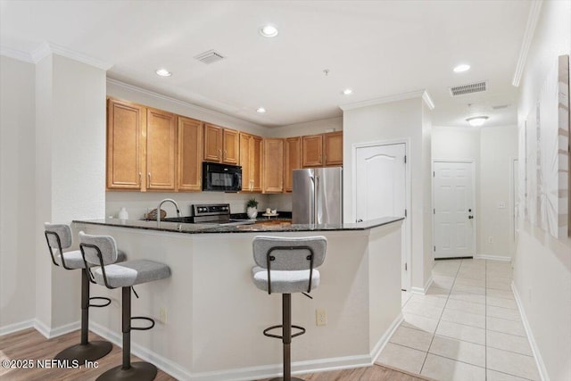 215 Bayberry Cir Unit 601, Saint Augustine, FL 32086 - kitchen with black microwave, freestanding refrigerator, range, a breakfast bar, and crown molding
