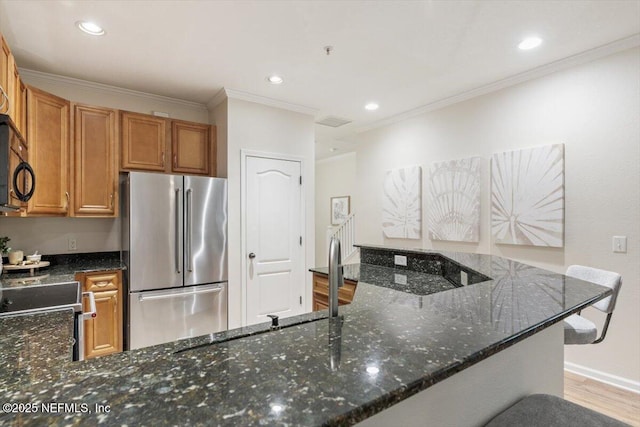 215 Bayberry Cir Unit 601, Saint Augustine, FL 32086 - kitchen with stainless steel appliances, wood finished floors, dark stone countertops, crown molding, and brown cabinetry