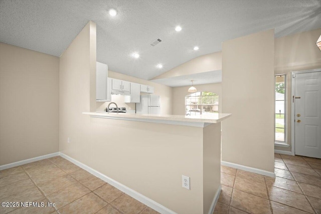 268 Southlake Dr, Saint Augustine, FL 32092 - kitchen featuring freestanding refrigerator, a peninsula, vaulted ceiling, white cabinetry, and light countertops