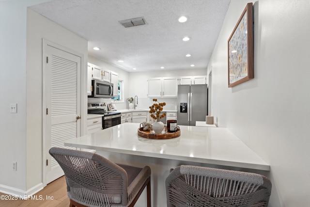 1578 Linkside Dr, Atlantic Beach, FL 32233 - kitchen featuring stainless steel appliances, a peninsula, light wood-style floors, a kitchen breakfast bar, and recessed lighting