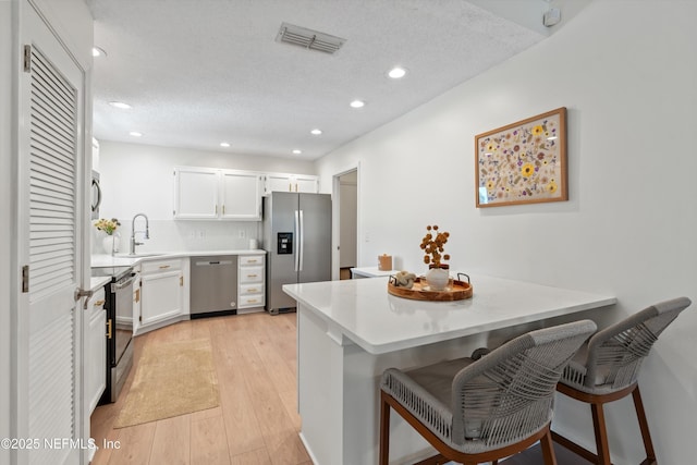1578 Linkside Dr, Atlantic Beach, FL 32233 - kitchen with stainless steel appliances, a peninsula, recessed lighting, a breakfast bar area, and white cabinets