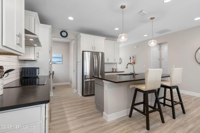 7 Los Lagos Blvd, Palm Coast, FL 32137 - kitchen featuring freestanding refrigerator, under cabinet range hood, dark countertops, black electric cooktop, and light wood-type flooring