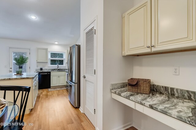 1803 Oakbreeze Ct, Jacksonville Beach, FL 32250 - kitchen with black dishwasher, cream cabinetry, freestanding refrigerator, light wood finished floors, and recessed lighting
