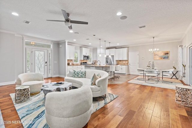 201 History Pl, Saint Augustine, FL 32095 - living room with crown molding, a chandelier, ceiling fan, a textured ceiling, and light wood-style flooring