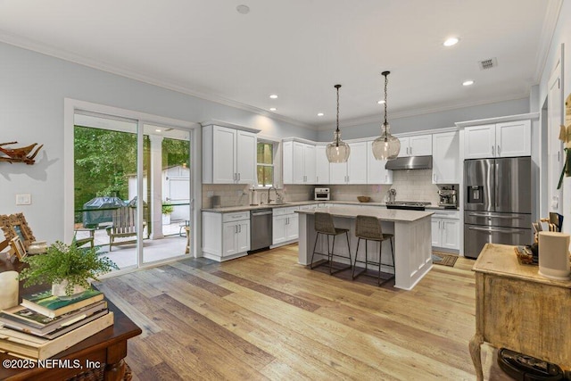 791 Paradise Ln, Atlantic Beach, FL 32233 - kitchen with appliances with stainless steel finishes, under cabinet range hood, light countertops, tasteful backsplash, and ornamental molding