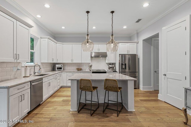 791 Paradise Ln, Atlantic Beach, FL 32233 - kitchen featuring appliances with stainless steel finishes, under cabinet range hood, a kitchen island, white cabinets, and crown molding