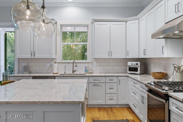 791 Paradise Ln, Atlantic Beach, FL 32233 - kitchen featuring under cabinet range hood, crown molding, stainless steel gas range oven, backsplash, and white cabinetry