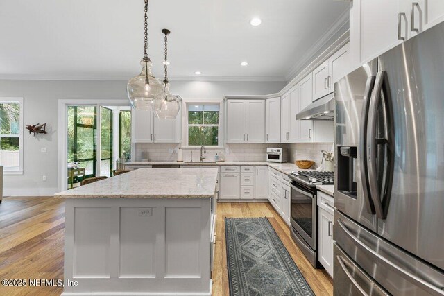 791 Paradise Ln, Atlantic Beach, FL 32233 - kitchen featuring stainless steel appliances, under cabinet range hood, a center island, plenty of natural light, and ornamental molding