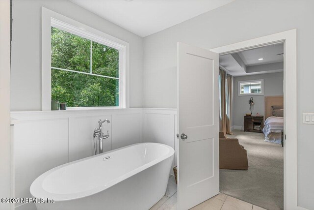 791 Paradise Ln, Atlantic Beach, FL 32233 - bathroom featuring a soaking tub, ensuite bathroom, a wainscoted wall, a decorative wall, and tile patterned flooring