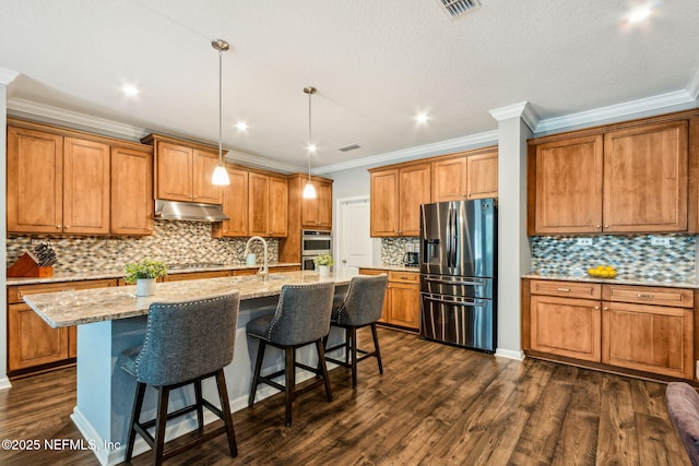 207 Hertford Bridge Way, Saint Johns, FL 32259 - kitchen with stainless steel appliances, under cabinet range hood, brown cabinetry, crown molding, and backsplash