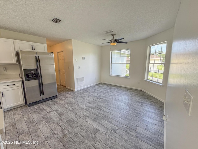 1736 Ashwood Cir, Middleburg, FL 32068 - kitchen featuring stainless steel refrigerator with ice dispenser, white cabinets, a ceiling fan, a textured ceiling, and light countertops