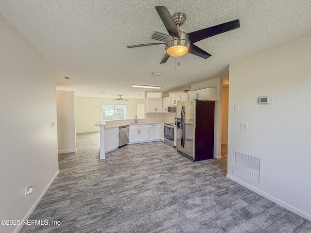 1736 Ashwood Cir, Middleburg, FL 32068 - kitchen with appliances with stainless steel finishes, ceiling fan, a textured ceiling, white cabinetry, and wood finished floors