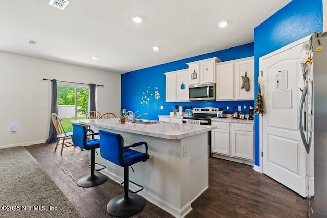 65490 Crested Heron Ct, Yulee, FL 32097 - kitchen featuring stainless steel appliances, light countertops, a kitchen breakfast bar, white cabinets, and a center island with sink