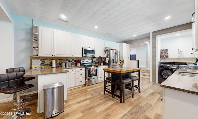 90 SE Forest St, Keystone Heights, FL 32656 - kitchen featuring stainless steel appliances, washing machine and dryer, white cabinetry, light wood-style flooring, and recessed lighting