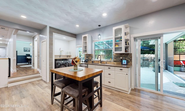 90 SE Forest St, Keystone Heights, FL 32656 - kitchen with washing machine and clothes dryer, white cabinetry, glass insert cabinets, light wood-style flooring, and dishwasher