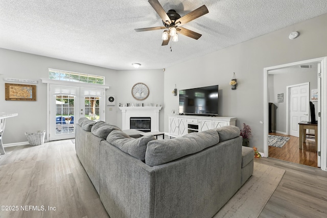 3172 Twilight Ct, Middleburg, FL 32068 - living room with ceiling fan, a glass covered fireplace, light wood-style floors, and a textured ceiling