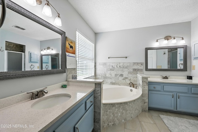3172 Twilight Ct, Middleburg, FL 32068 - full bath featuring two vanities, a textured ceiling, a garden tub, a stall shower, and tile patterned flooring