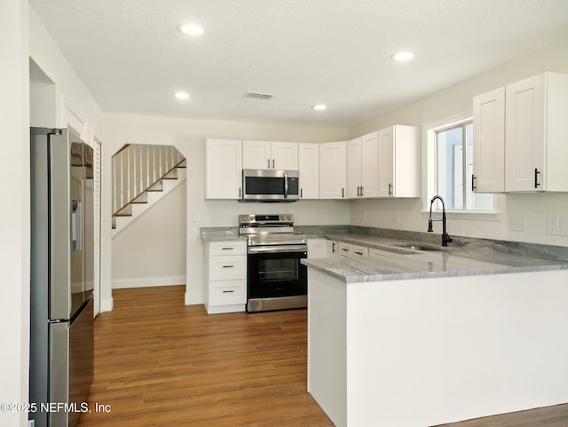 6615 Camelot Ct, Keystone Heights, FL 32656 - kitchen featuring stainless steel appliances, a peninsula, dark wood-style flooring, white cabinets, and recessed lighting