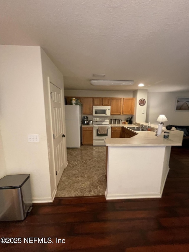 8550 Argyle Business Loop Unit 906, Jacksonville, FL 32244 - kitchen with white appliances, a peninsula, dark wood-style floors, light countertops, and brown cabinets