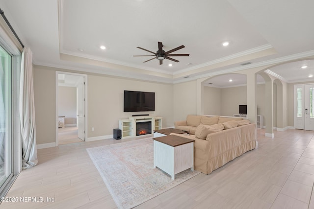 37 Tobago Ln, Saint Augustine, FL 32092 - living room featuring arched walkways, a raised ceiling, ceiling fan, ornamental molding, and a glass covered fireplace