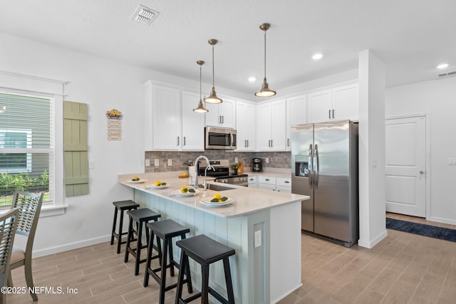 67 Carmella Ct, Saint Augustine, FL 32092 - kitchen with appliances with stainless steel finishes, light countertops, a peninsula, light wood-type flooring, and tasteful backsplash
