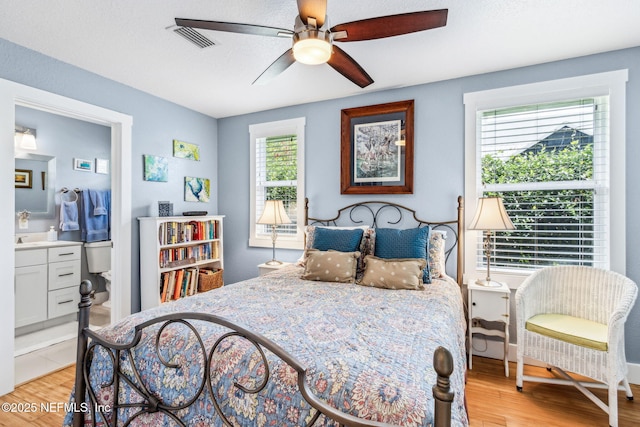 111 S 4th St, Fernandina Beach, FL 32034 - bedroom with light wood-style flooring, connected bathroom, and ceiling fan