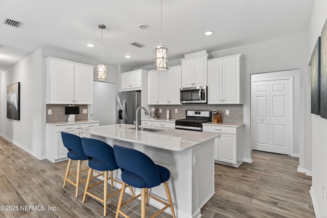 204 Bryson Dr, Fruit Cove, FL 32259 - kitchen featuring stainless steel appliances, decorative backsplash, a breakfast bar area, light wood-type flooring, and white cabinets