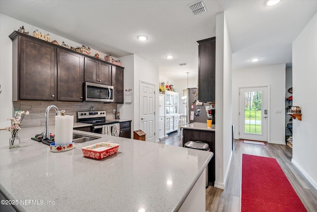 5 Bud Hollow Dr, Palm Coast, FL 32137 - kitchen featuring stainless steel appliances, dark brown cabinetry, backsplash, recessed lighting, and light wood-type flooring