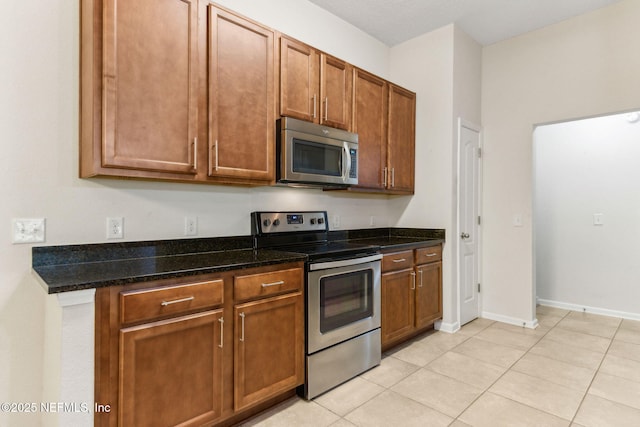 218 Larkin Pl Unit 110, Saint Johns, FL 32259 - kitchen featuring appliances with stainless steel finishes, dark stone counters, brown cabinets, and light tile patterned flooring