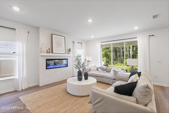 73 Ripple Rd, Saint Johns, FL 32095 - living room featuring wood finished floors, a textured ceiling, a glass covered fireplace, and recessed lighting