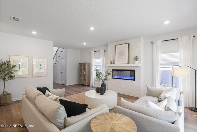 73 Ripple Rd, Saint Johns, FL 32095 - living area with stairs, a glass covered fireplace, recessed lighting, wood finished floors, and a textured ceiling