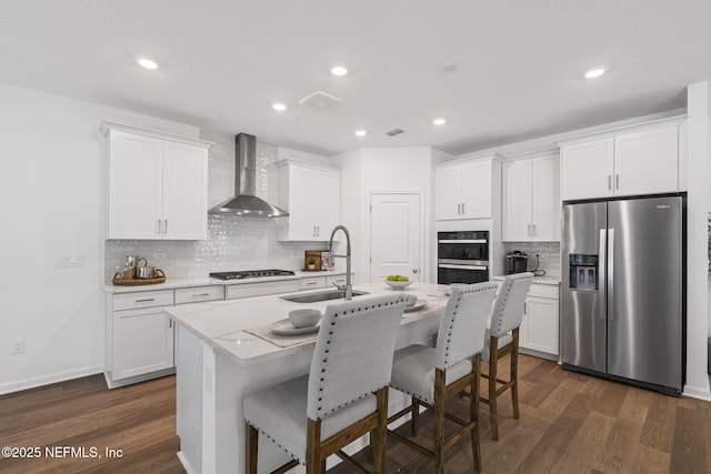 73 Ripple Rd, Saint Johns, FL 32095 - kitchen with stainless steel appliances, wall chimney range hood, tasteful backsplash, dark wood-type flooring, and an island with sink