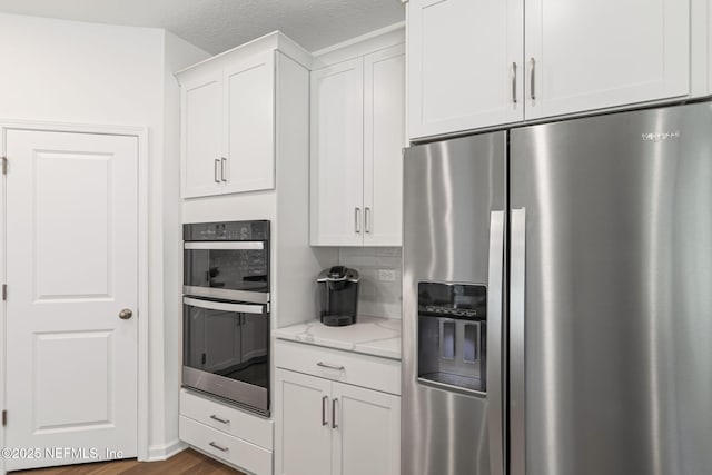 73 Ripple Rd, Saint Johns, FL 32095 - kitchen with appliances with stainless steel finishes, light stone countertops, white cabinets, dark wood-type flooring, and decorative backsplash