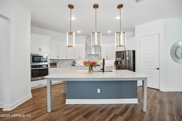 959 Crosswater Lake Dr, Ponte Vedra, FL 32081 - kitchen with appliances with stainless steel finishes, wall chimney exhaust hood, tasteful backsplash, dark wood-style floors, and white cabinetry